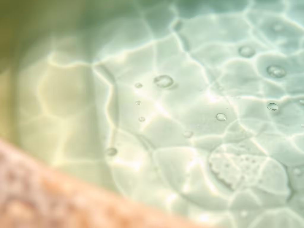 Eau thermale corse claire avec dépôts minéraux, bassin naturel en pierre