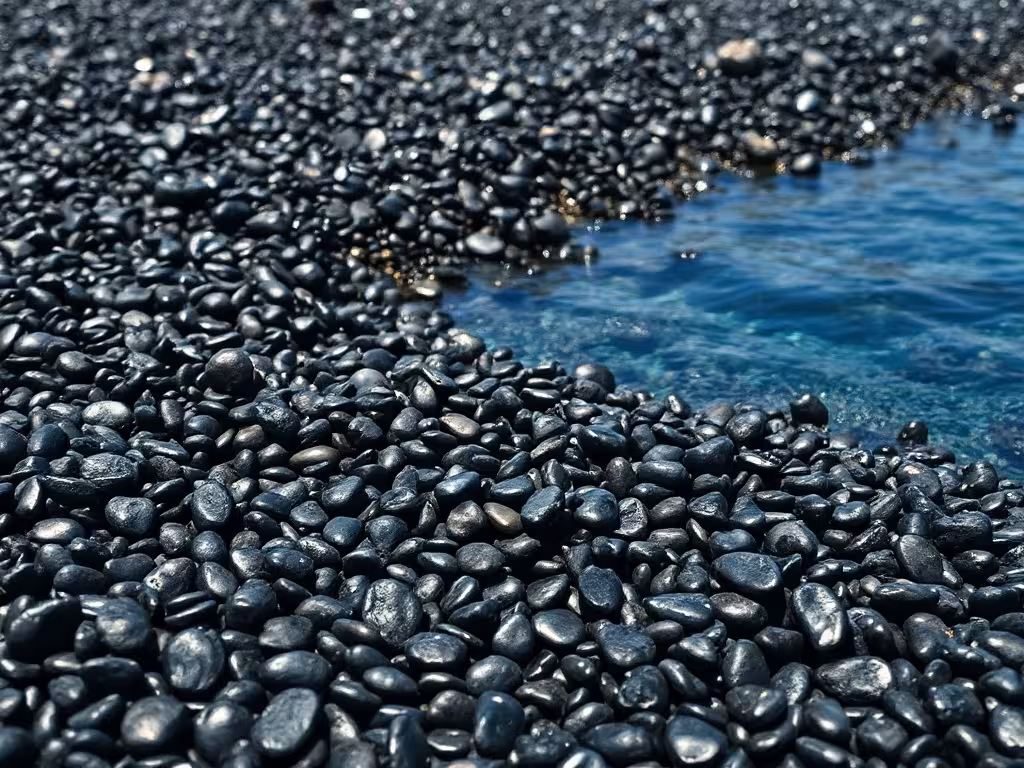 Les galets volcaniques noirs de la plage de Nonza, contrastant avec l'eau turquoise méditerranéenne.